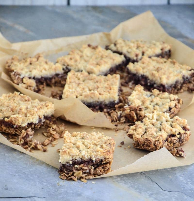 A smattering of gluten-free oatmeal bars with layers of cherry preserves cut out in squares.