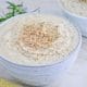 Creamy Vegan Cauliflower Soup in a light blue bowl on a marble table top with sesame seeds.